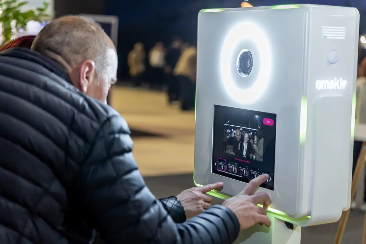 Un participant choisit une option sur l'écran tactile de la borne Smakk, anneau lumineux allumé