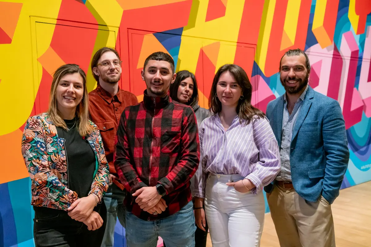 L'équipe Shootnbox au complet, six personnes souriantes devant une fresque colorée